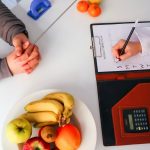 Top view of a dietitian planning a healthy diet with fresh fruits on the table, focusing on health and nutrition.